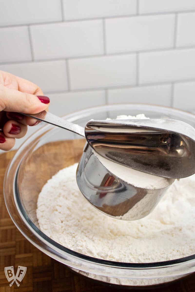 Leveling off a measuring cup full of flour.