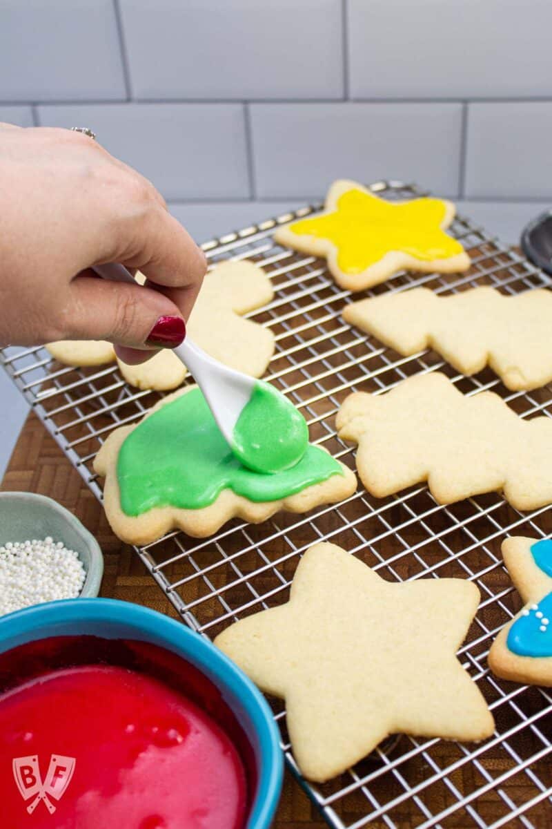 Icing a Christmas tree-shaped sugar cookie.