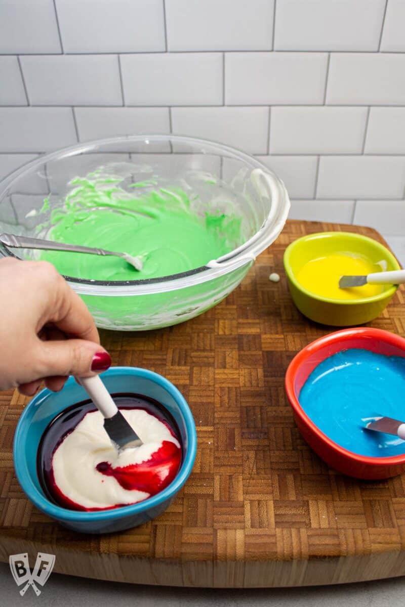 Mixing bowls of green, yellow, blue, and red icing.