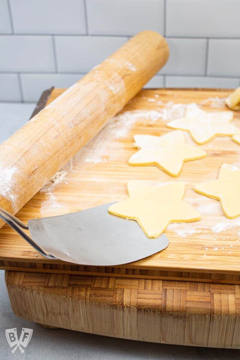 Metal spatula scooping up star-shaped sugar cookie dough.