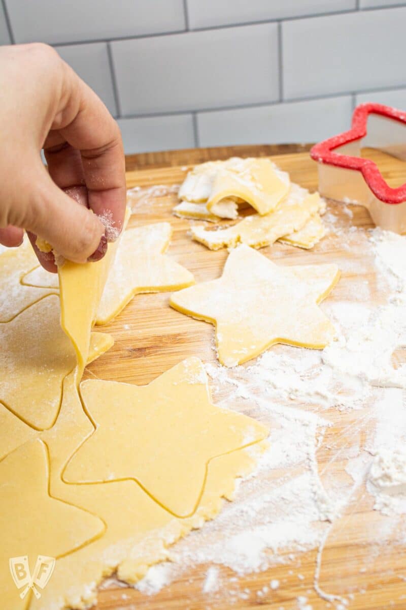 Removing excess cookie dough from cut out star shapes.