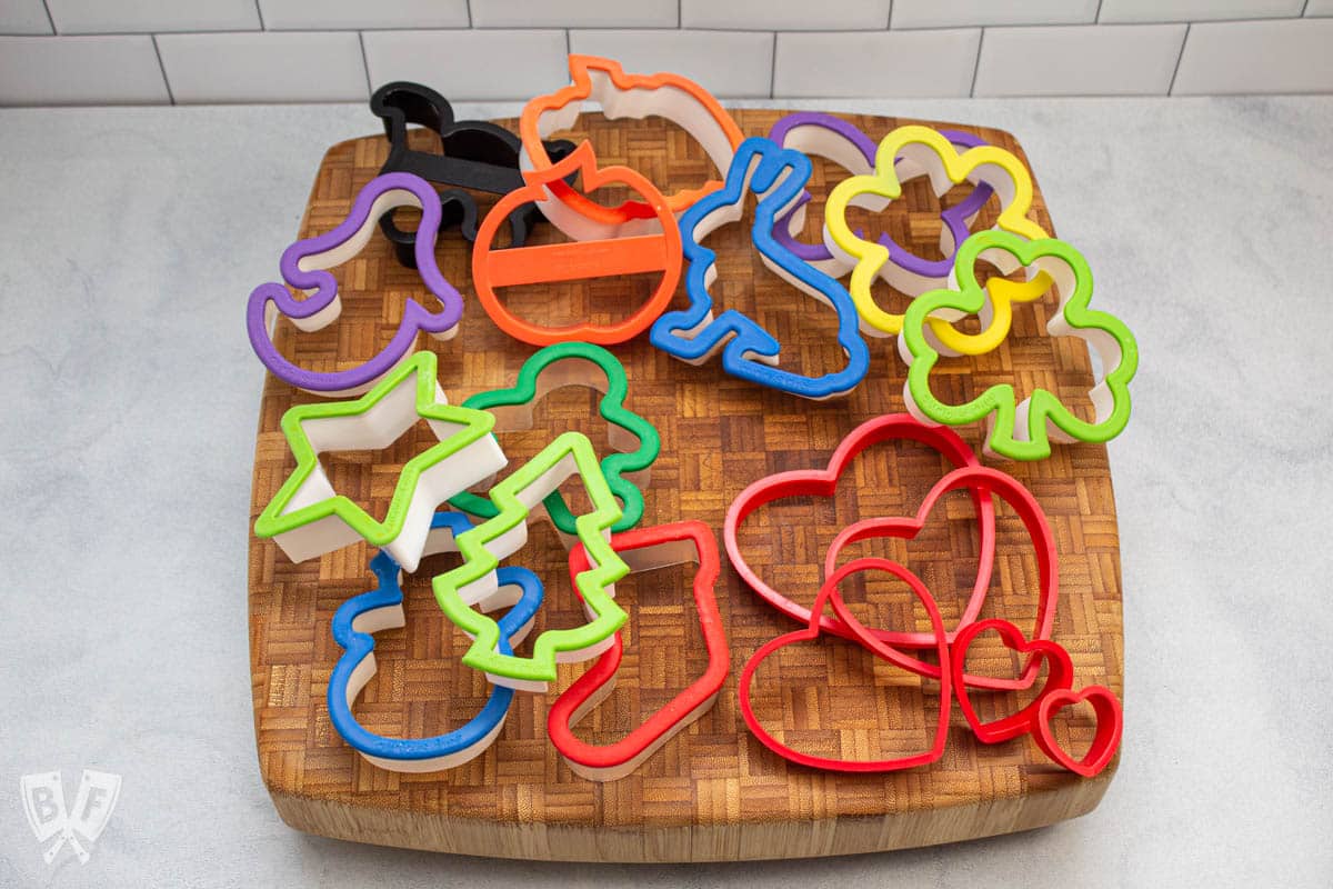 Assortment of holiday cookie cutters on a cutting board.