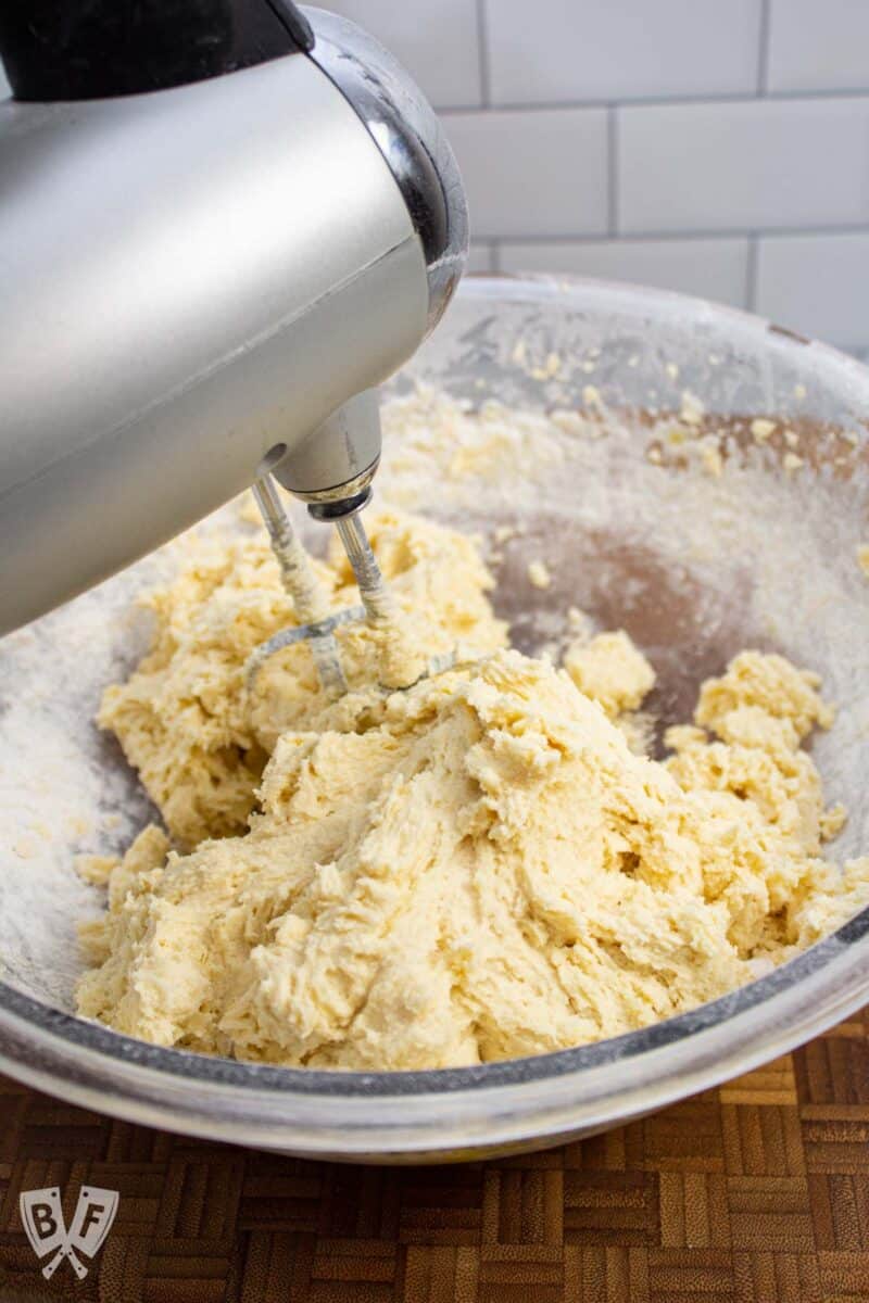 Cookie dough coming together in a bowl with an electric mixer.