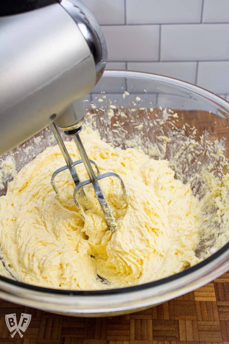Electric hand mixer combining ingredients for cookie dough.