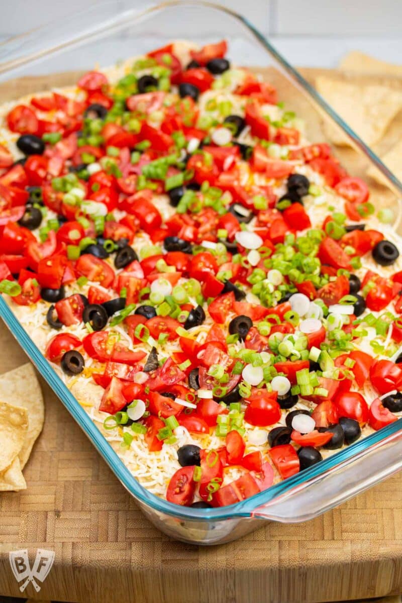 Serving dish of layered taco dip surrounded by tortilla chips.