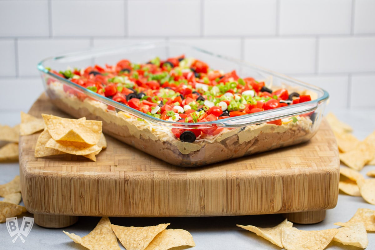 ¾ vies of a layered taco dip with refried beans surrounded by tortilla chips.
