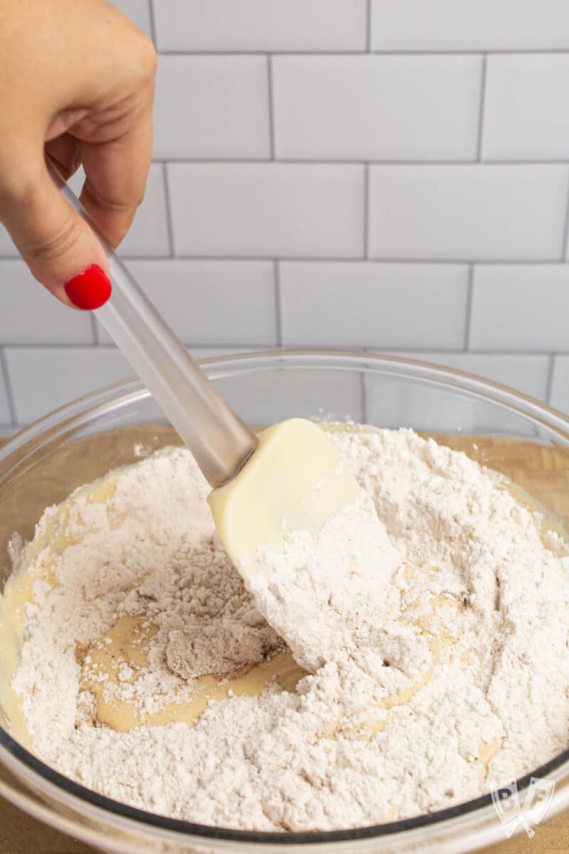 Incorporating wet and dry ingredients together in a bowl with a silicone spatula.