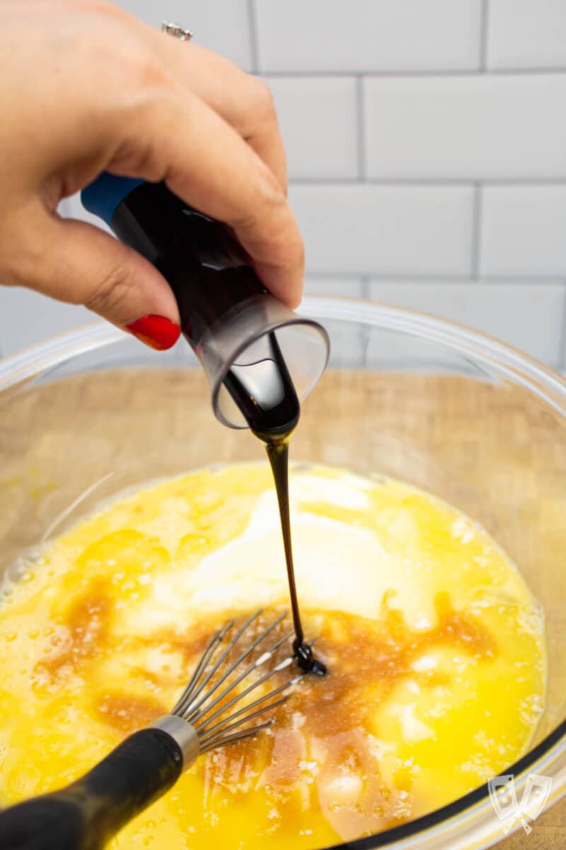 Pouring molasses into a bowl of wet ingredients for a gingerbread pancake recipe.