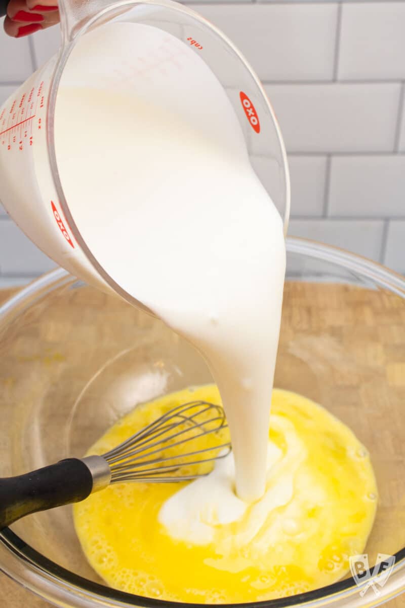 Pouring buttermilk into a bowl of beaten eggs.