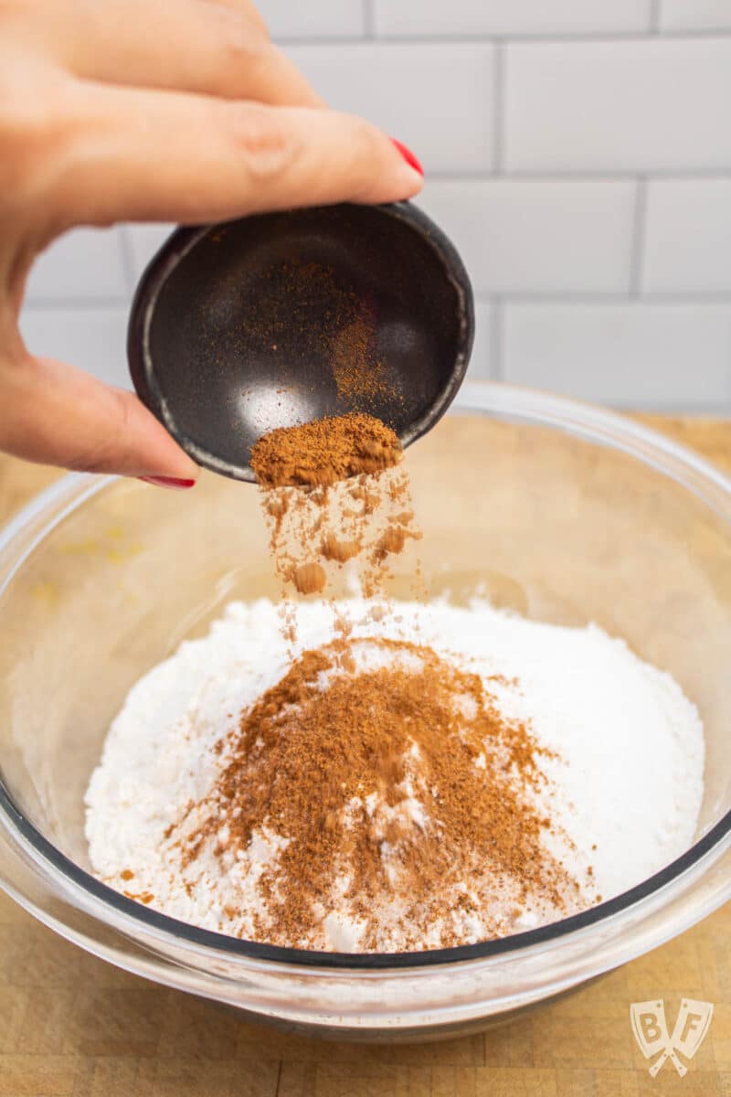 Adding ground nutmeg to a bowl of dry pancake ingredients.