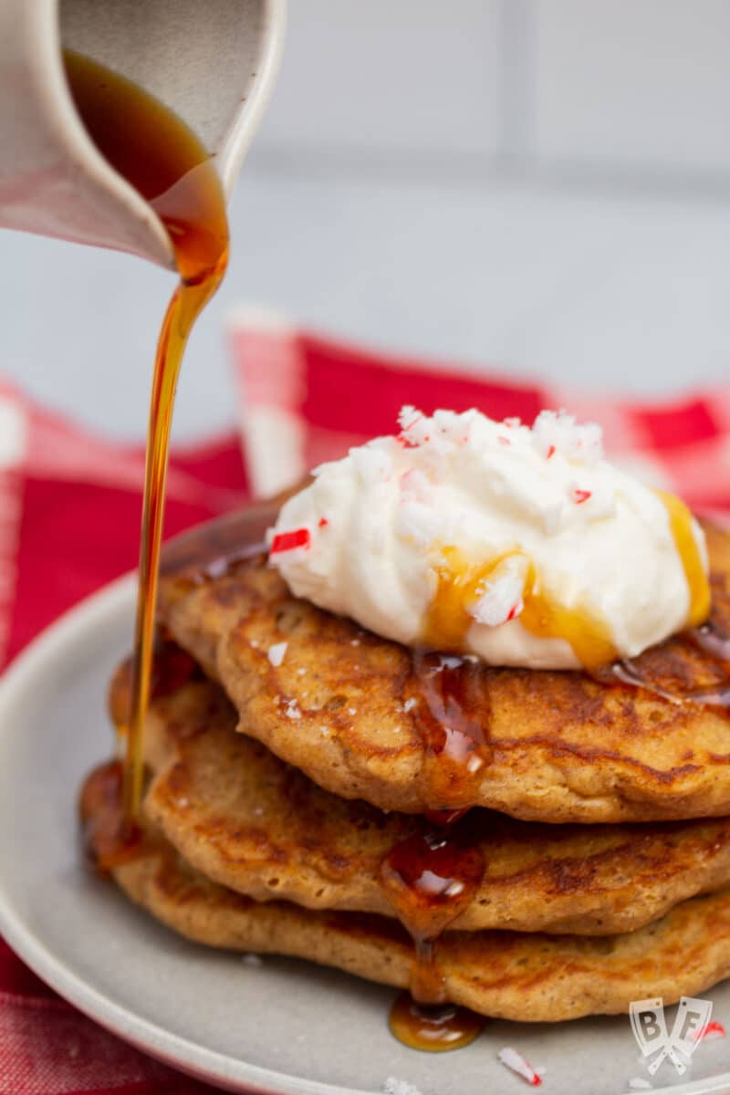 Drizzling maple syrup over a stack of gingerbread pancakes.