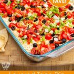 Overhead view of a layered taco dip with refried beans. Text overlay says "game day fave!".