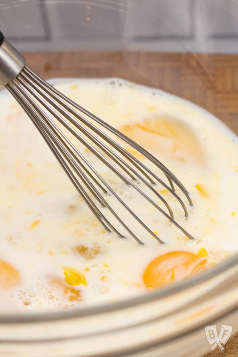 Whisking milk and eggs together in a bowl.