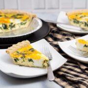 Close-up of slices of spinach and cheddar quiche on plates with forks.