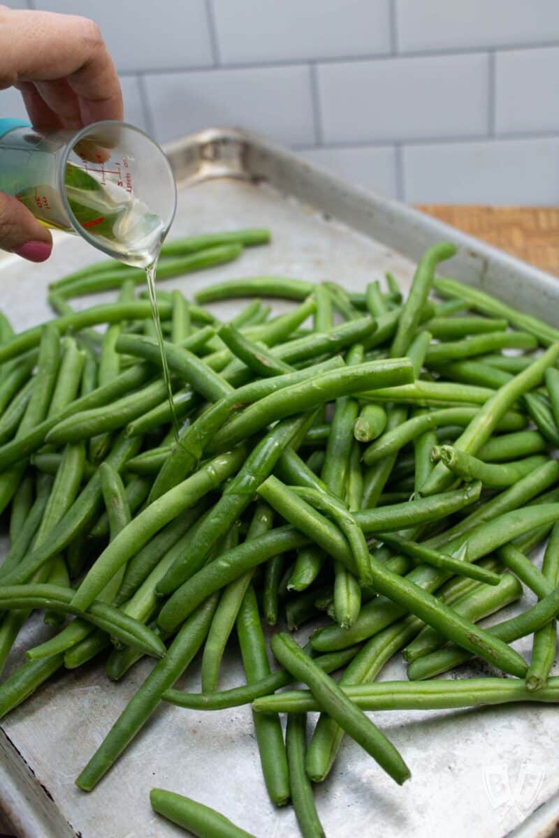 Drizzling fresh green beans with oil.