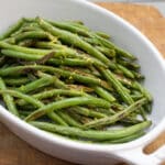 Serving dish with roasted green beans and lemon zest.