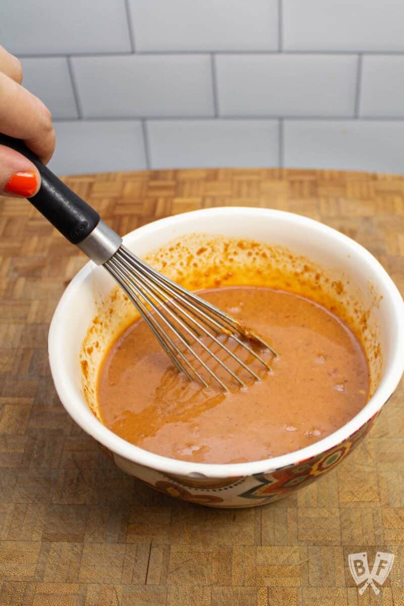 Whisking together peanut sauce ingredients in a bowl.