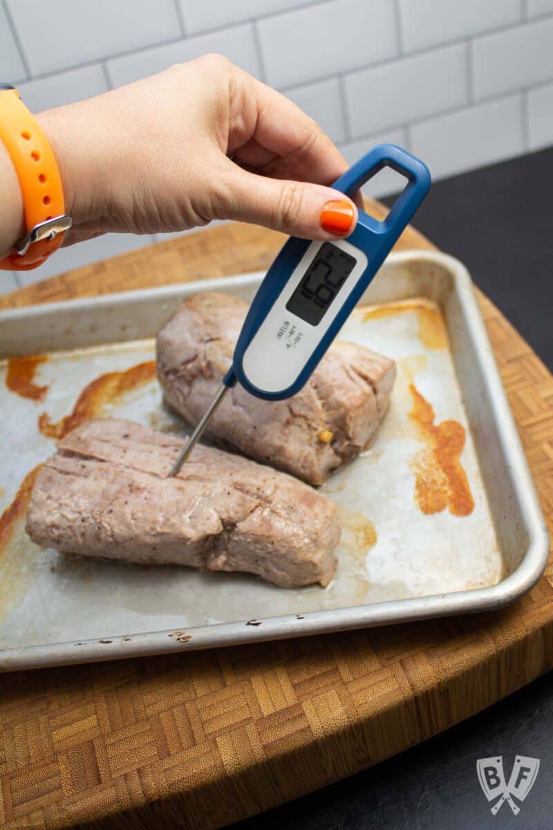 Checking the internal temperature of pork tenderloin with an instant-read thermometer.