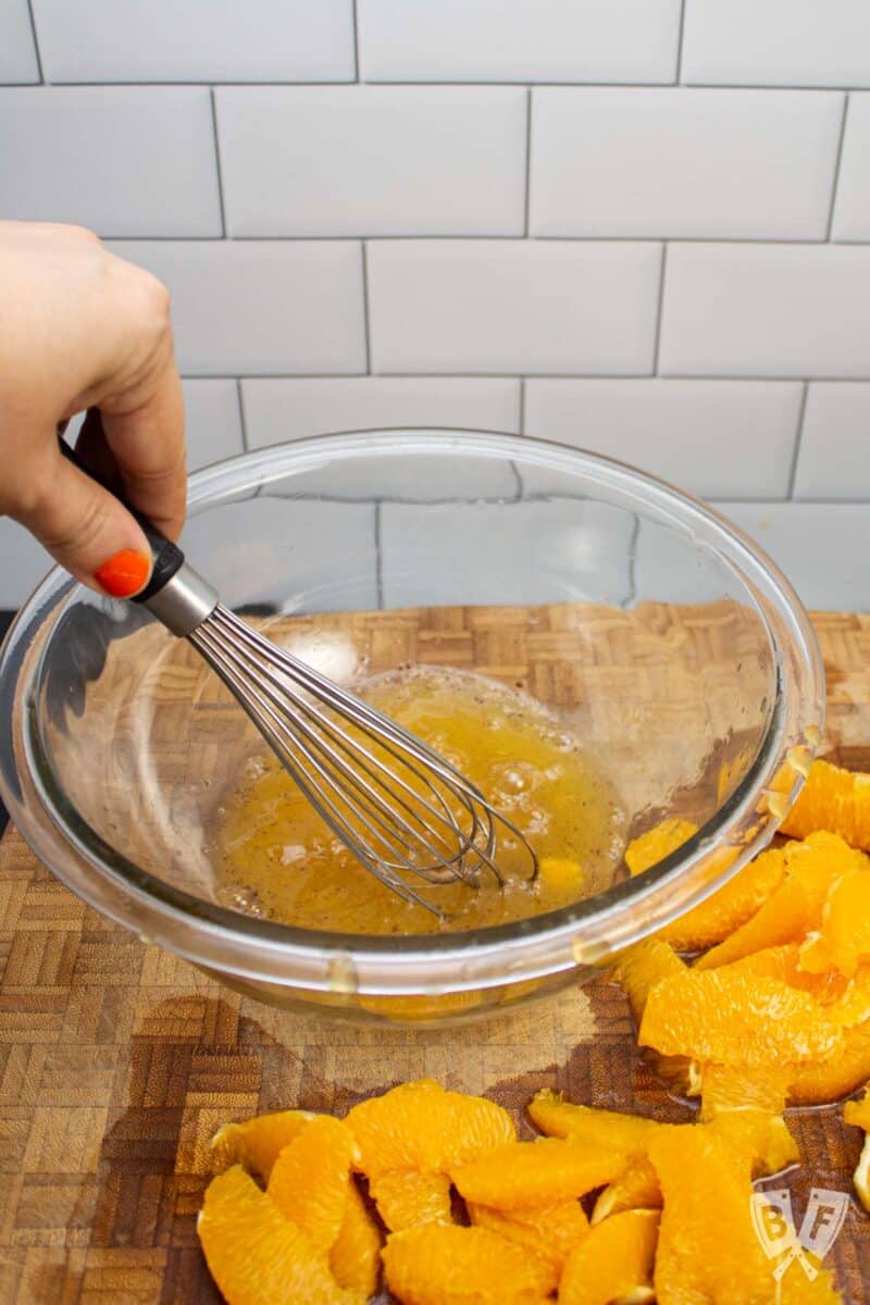 Whisking orange juice with allspice an honey in a bowl.