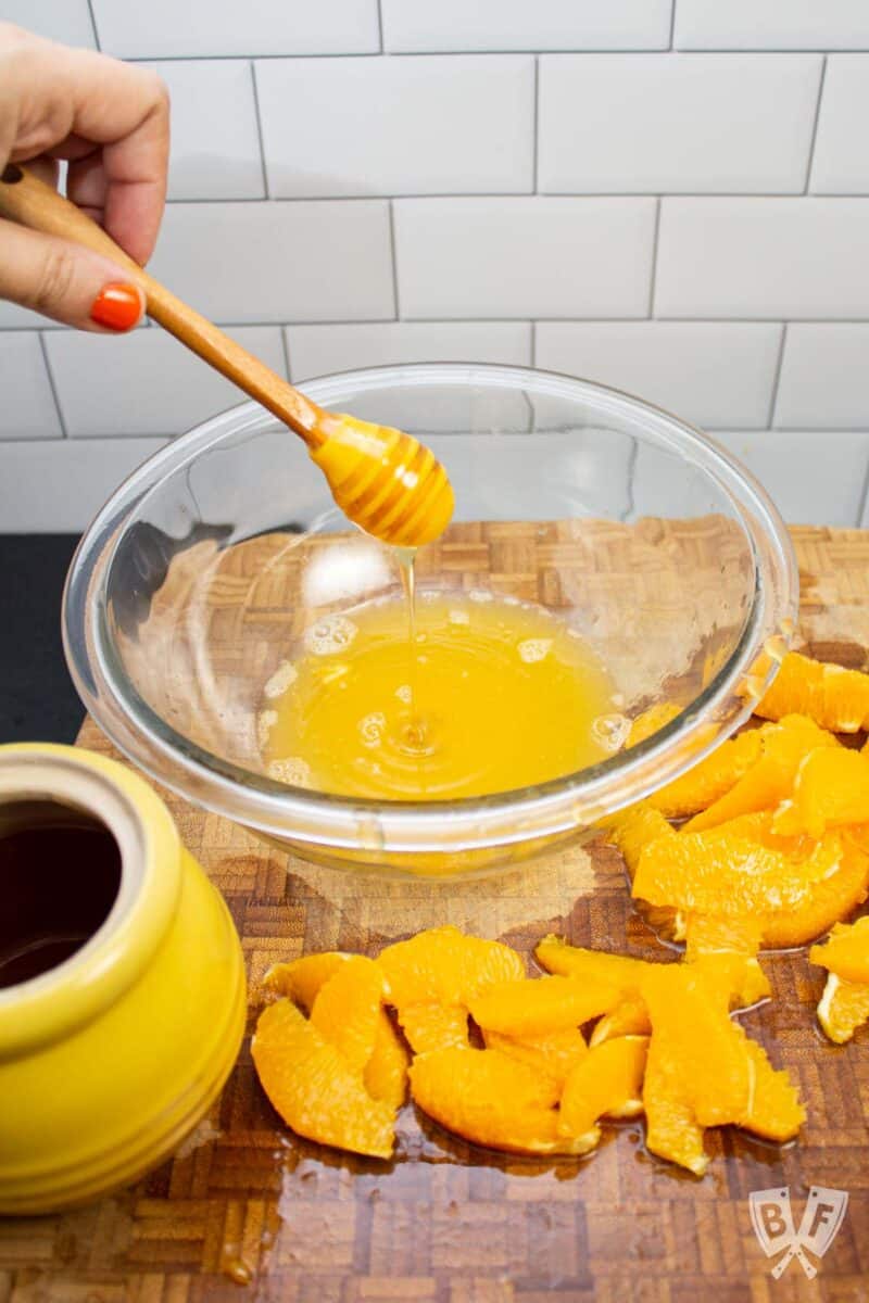 Drizzling honey into a bowl of orange juice.