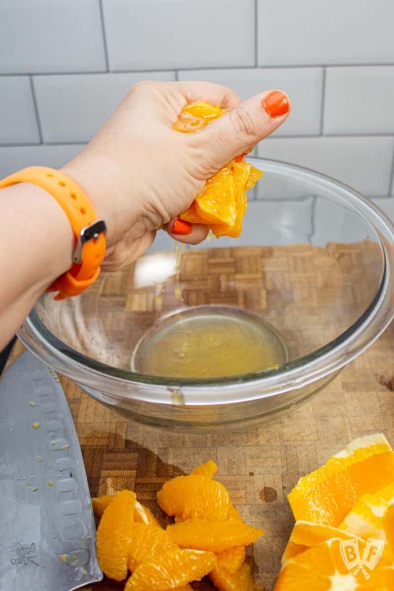 Squeezing an orange over a bowl.