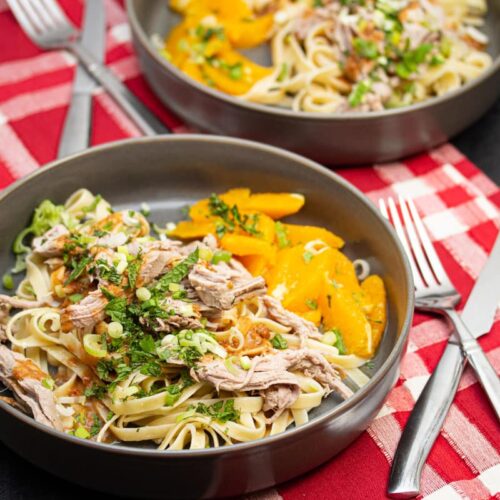 Peanut noodles with shredded pork, fresh herbs, and honeyed oranges.
