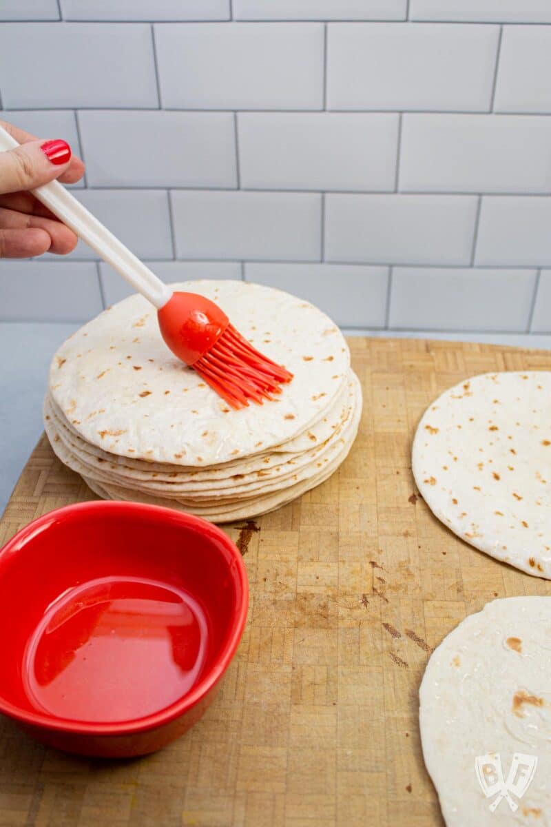 Brushing flour tortillas with cooking oil.