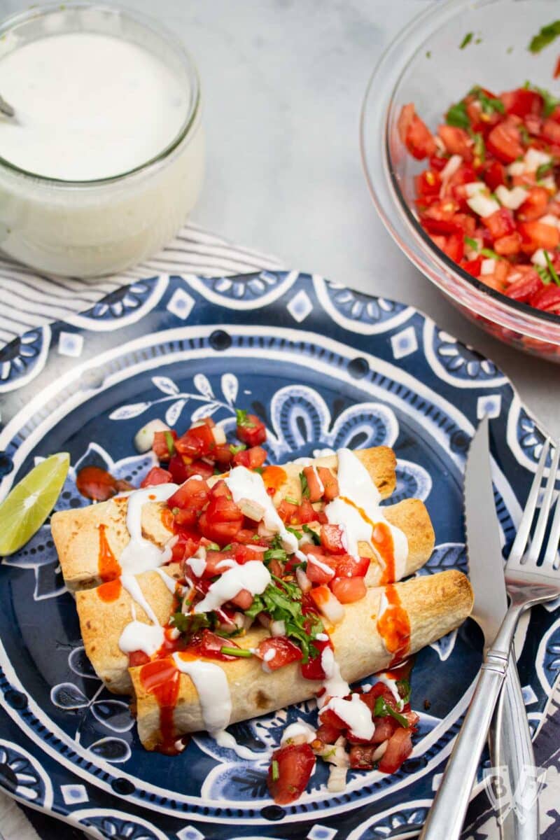 Plate of baked taquitos with pico de gallo and lime crema.