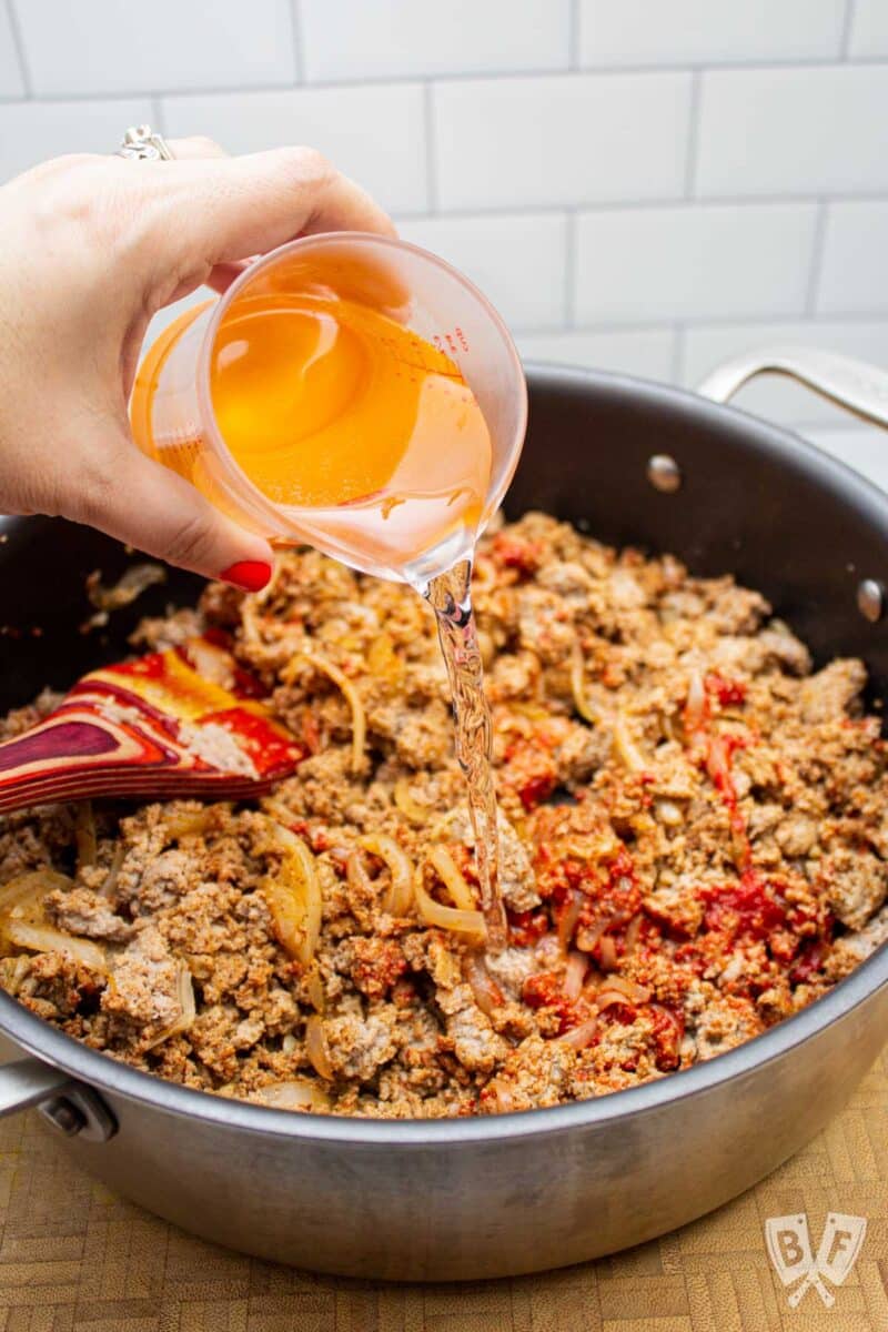 Adding water to taquito filling in a pan.