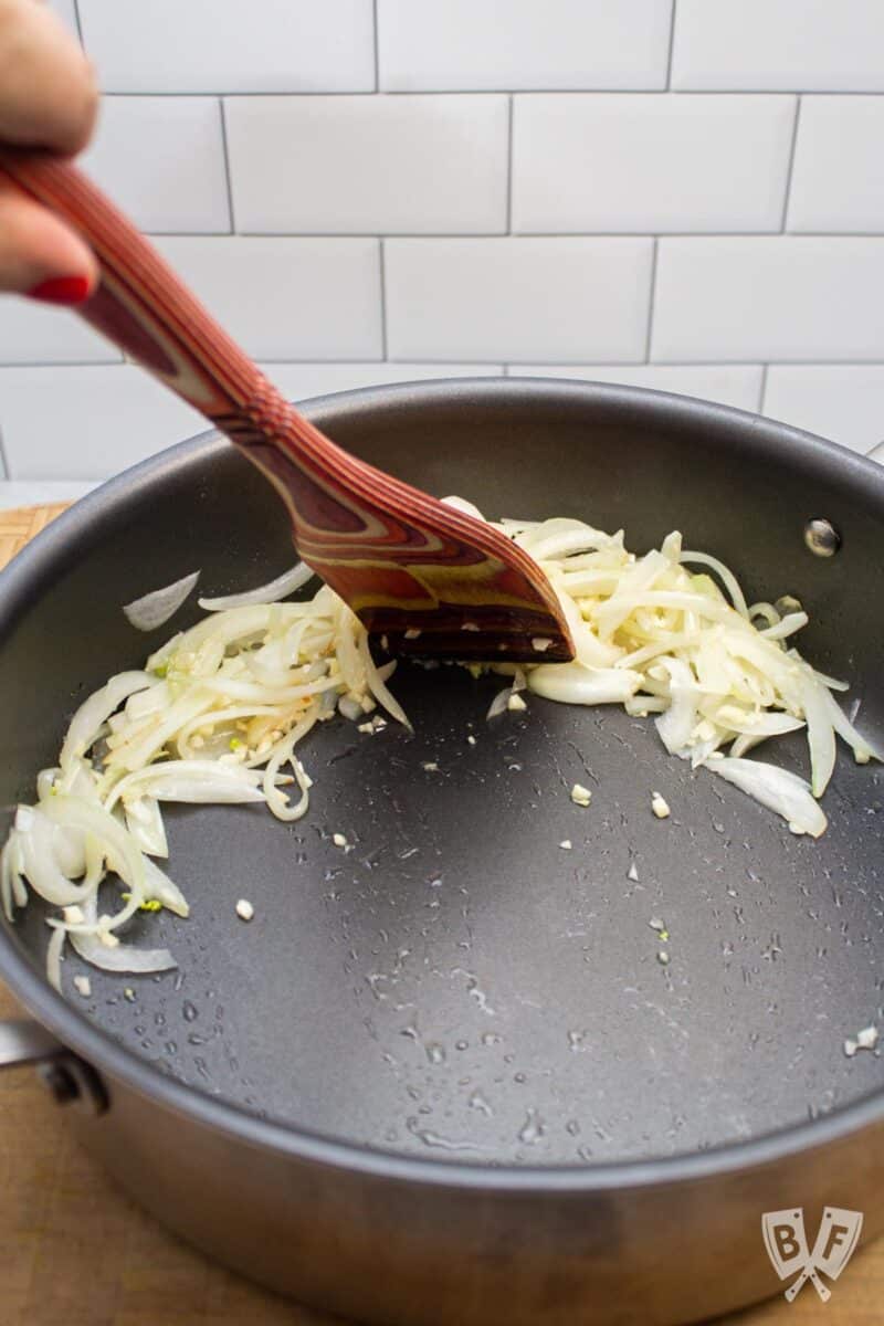 Scooting sautéed onions and garlic to the edge of a pan.