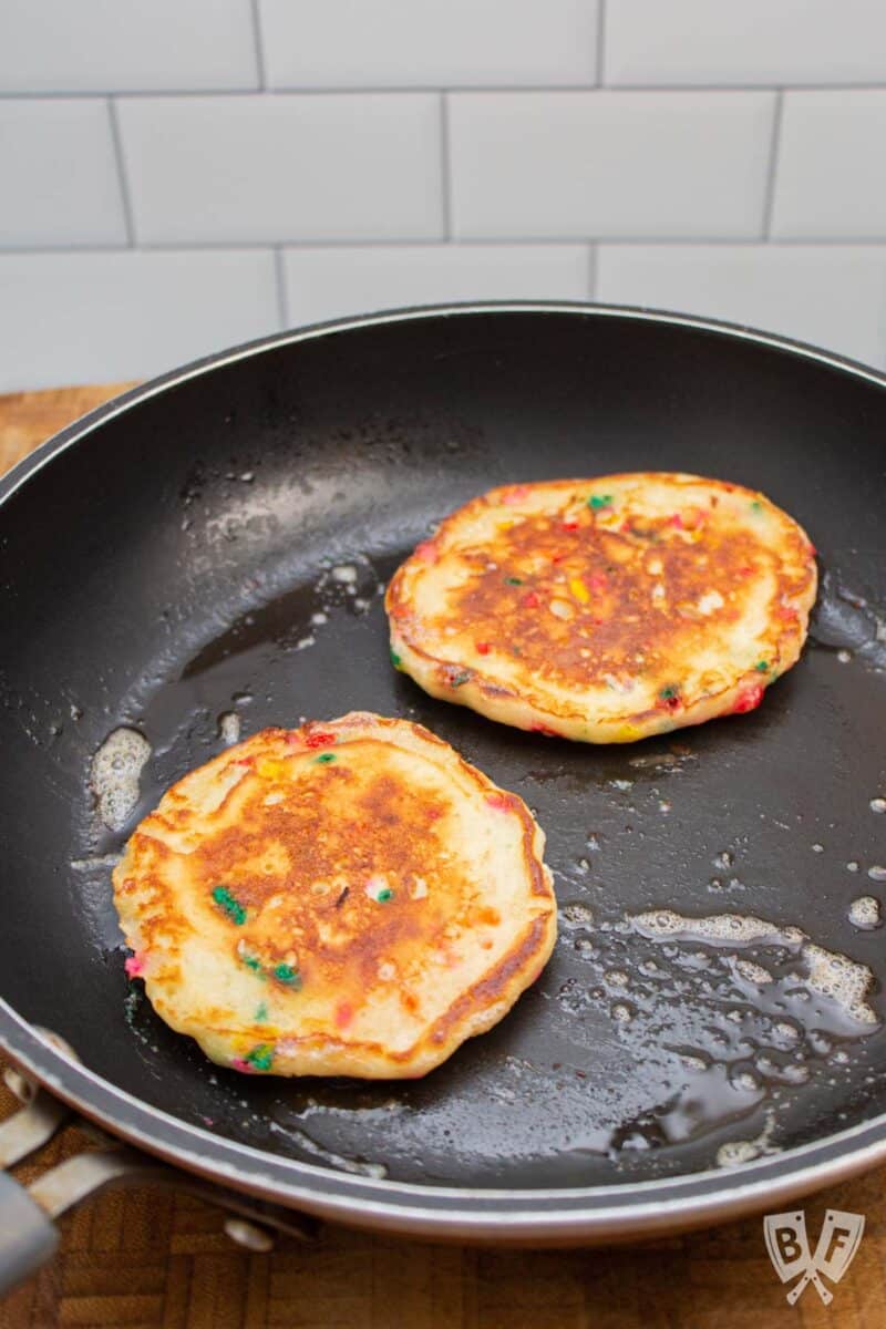 Two birthday cake pancakes in a skillet.