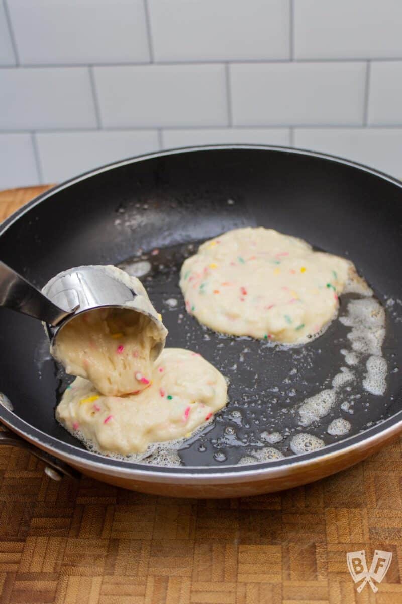 Portioning out funfetti pancake batter into a nonstick skillet.