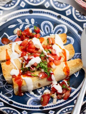 Plate of taquitos topped with pico de gallo.