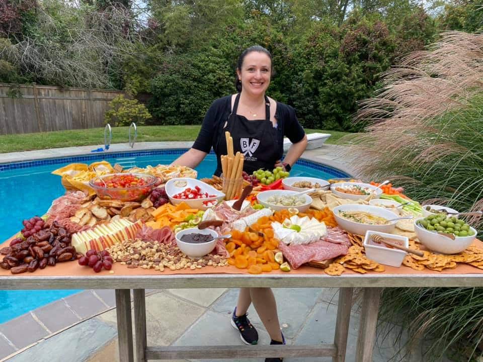 Ashley Covelli standing behind a massive charcuterie table spread