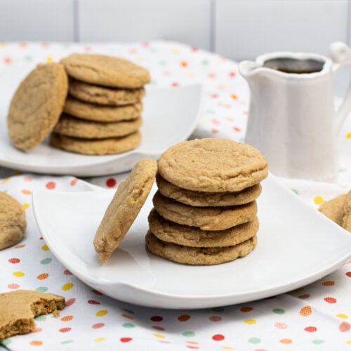 Maple cookies on plates with a pitcher of maple syrup alongside.