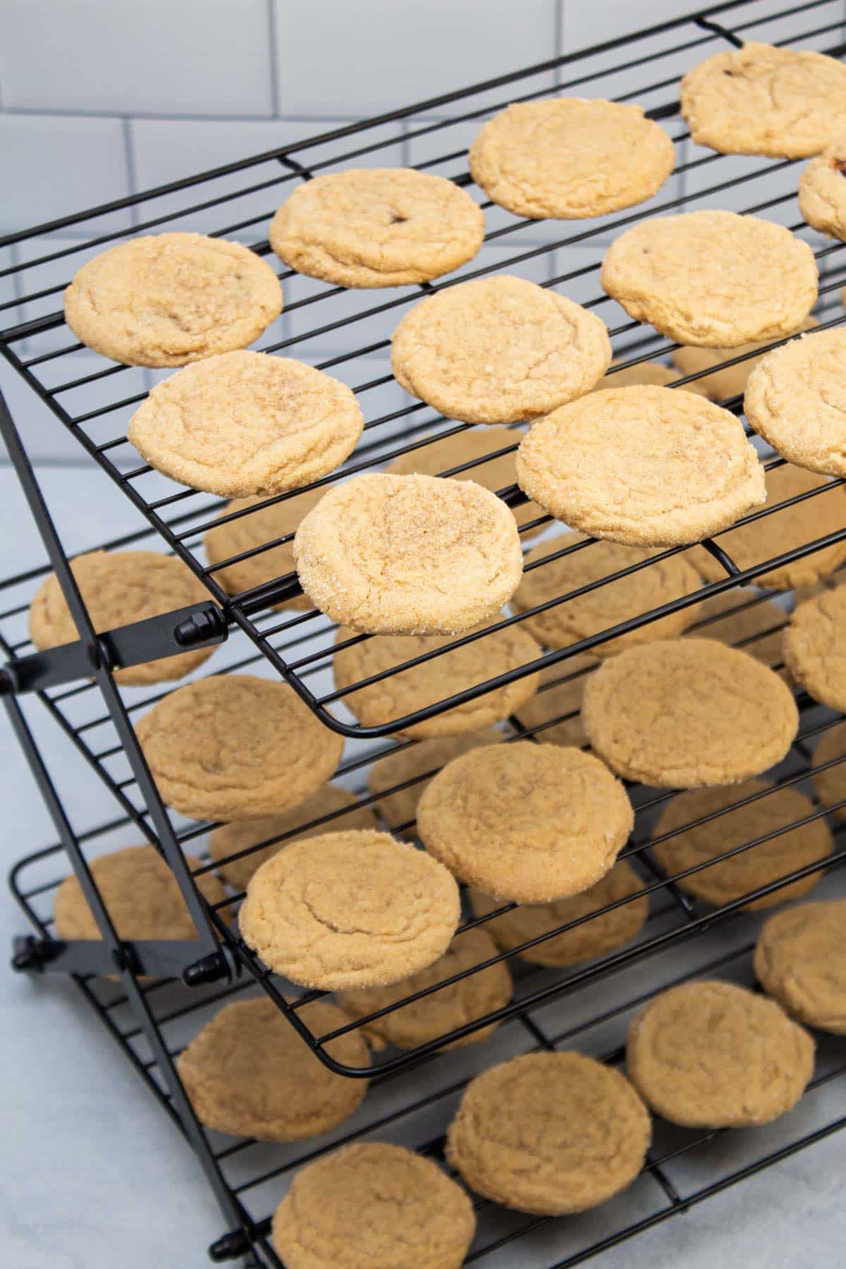 Three tiers of cooling racks filled with freshly baked cookies.