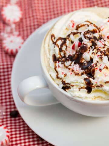 Peppermint mocha in a mug garnished with chocolate and peppermint candies.
