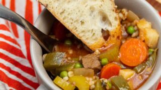 Two bowls of old fashioned beef stew with sliced bread served alongside.