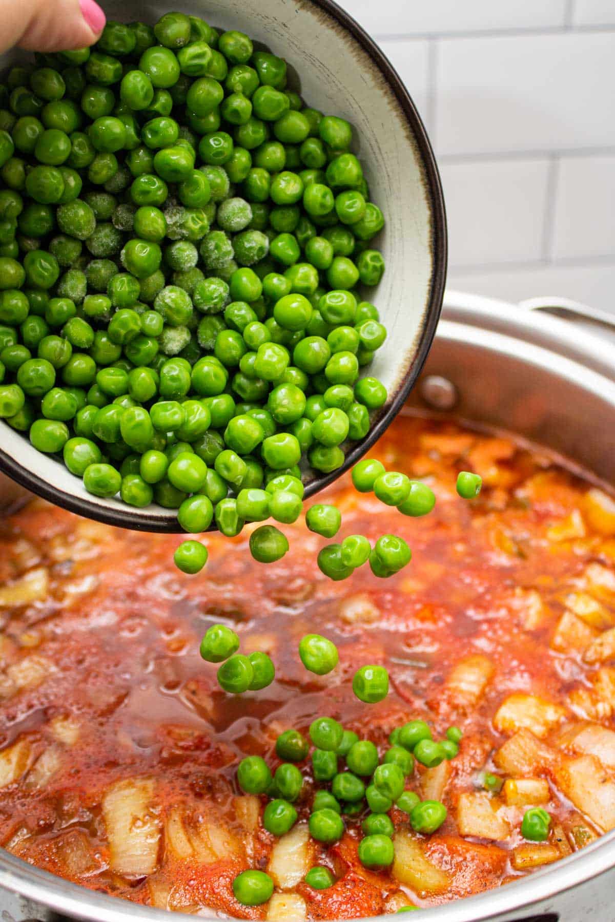 Adding peas to a pot of beef stew.