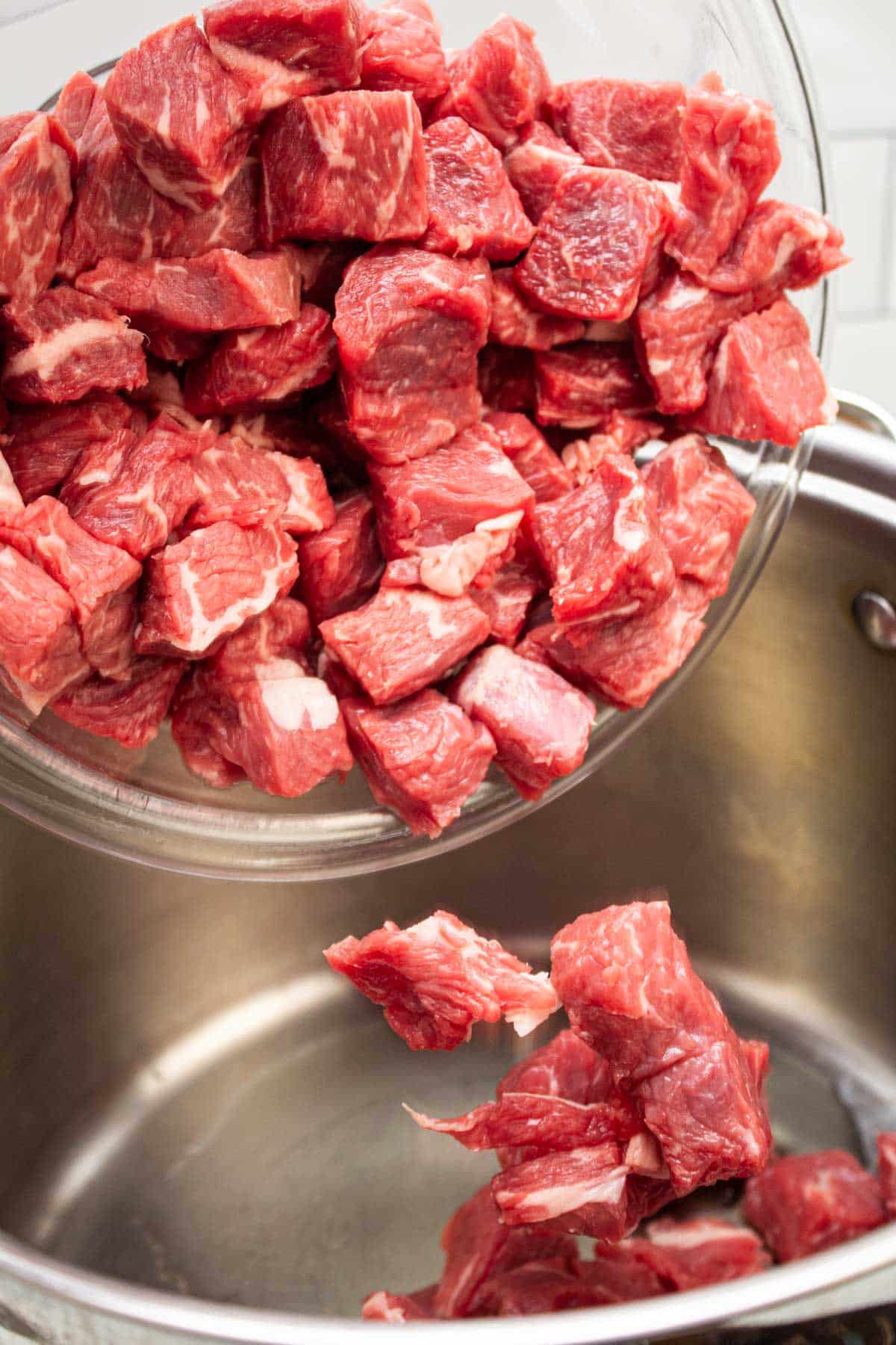 Adding beef cubes to a pot.
