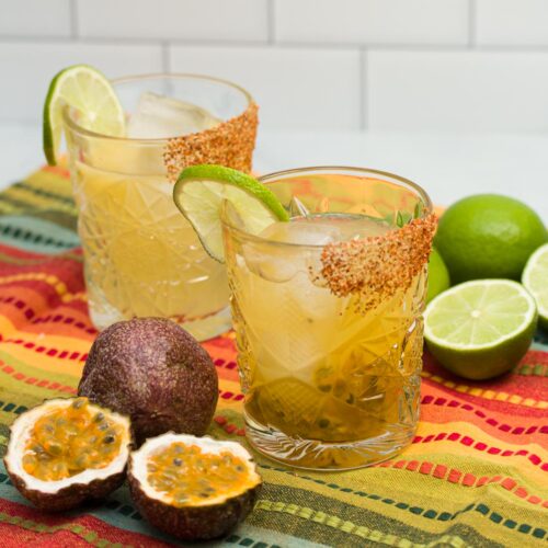 Two passionfruit margaritas with ingredients alongside.