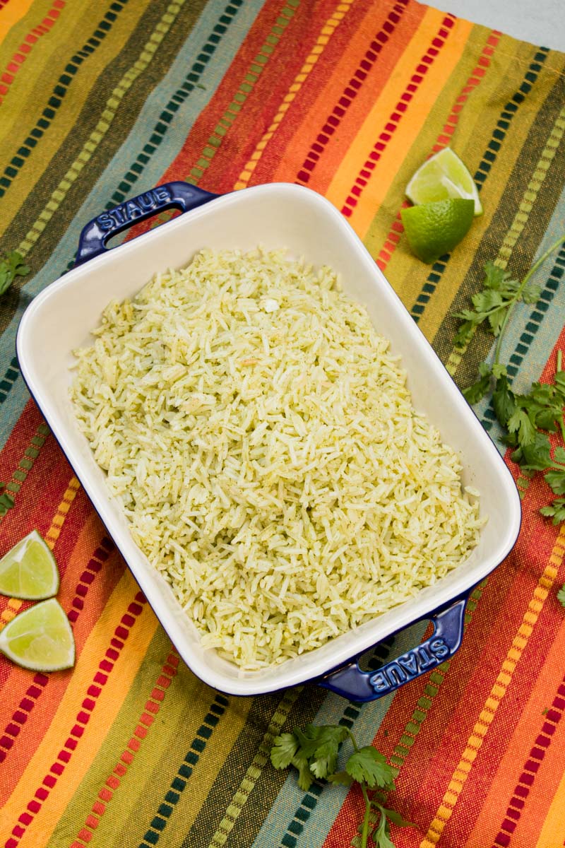 Serving dish of cilantro lime rice with lime wedge garnishes alongside.