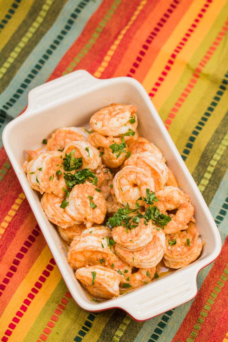 Serving dish of cooked shrimp garnished with chopped parsley.
