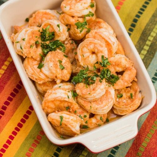 Serving dish of cooked shrimp garnished with chopped parsley.