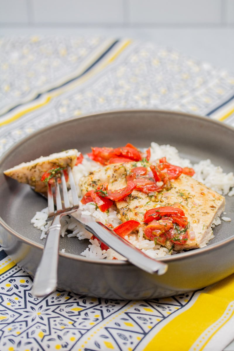 Cutting a bite of chicken cutlet with tomato-dill relish.