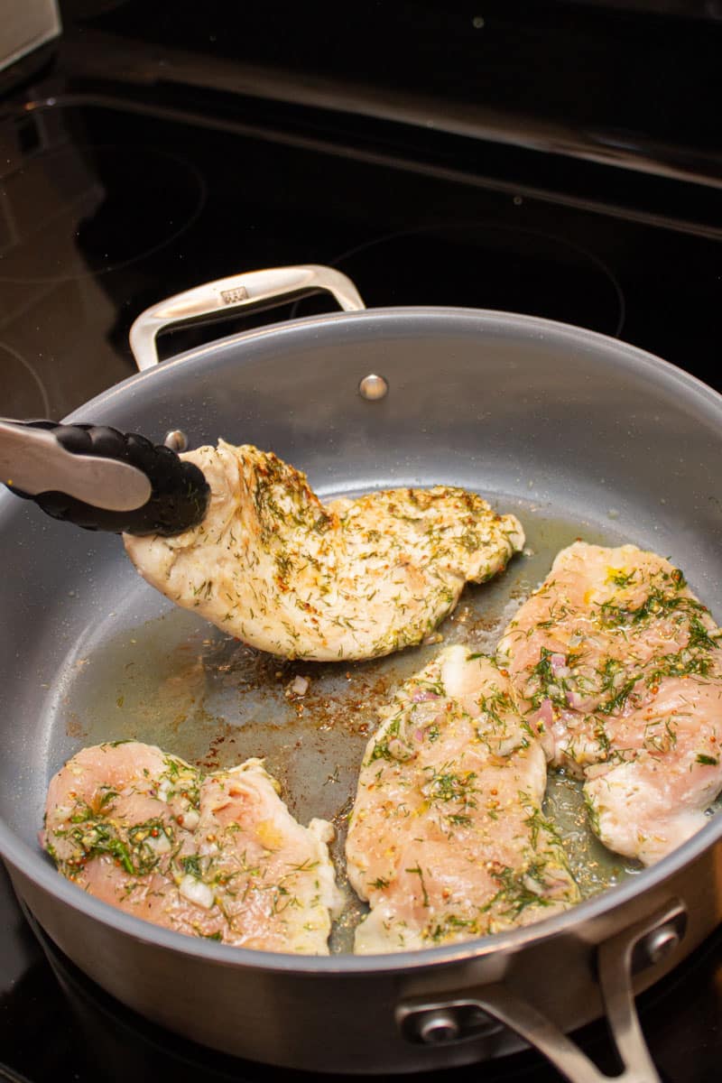Flipping chicken paillards over in a pan.