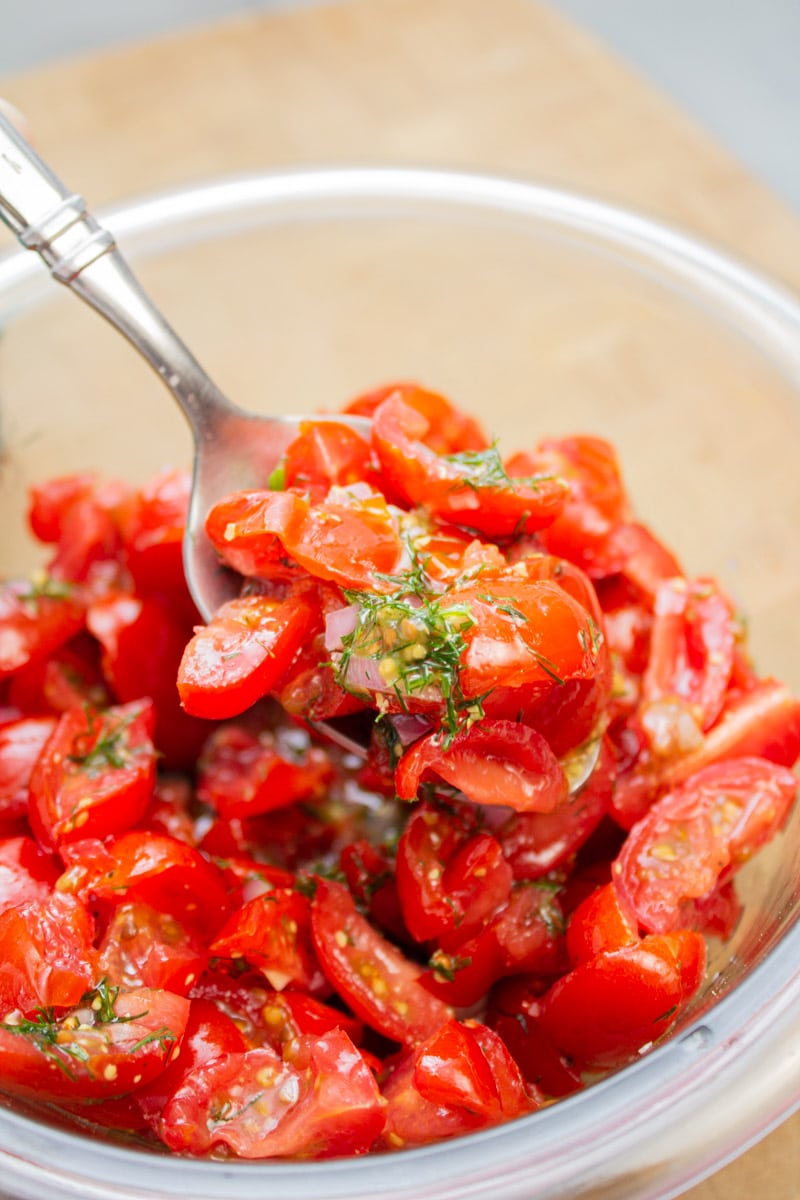 Lifting a spoon of tomato-dill relish from a bowl.
