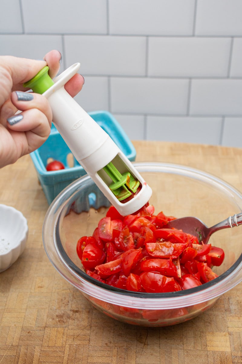 Using a tool to cut grape tomatoes into quarters.