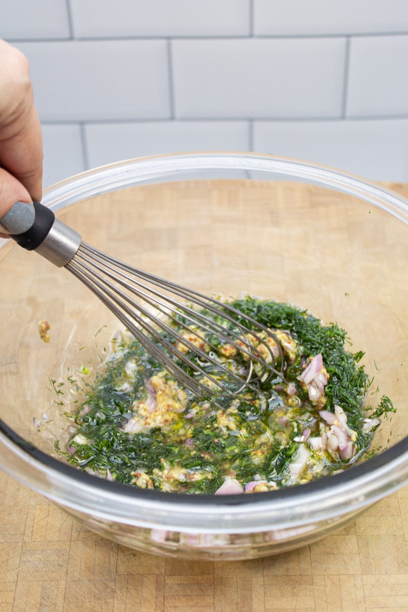 Whisking together a shallot and dill vinaigrette.
