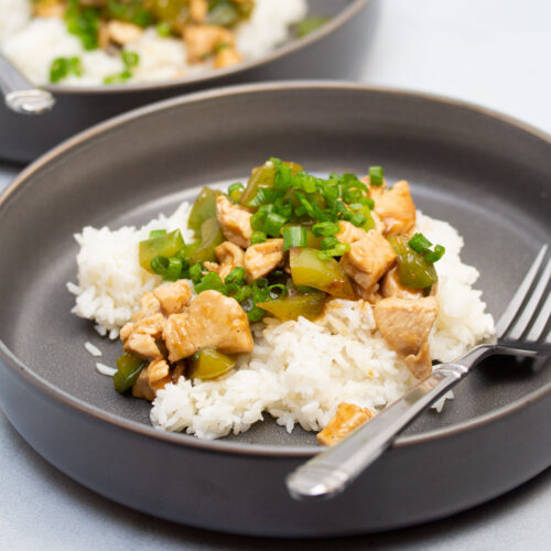 Chicken and bell pepper stir-fry served over white rice.